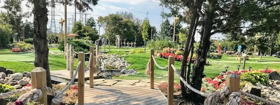 Wooden bridge walkway through landscaped mini golf gardens