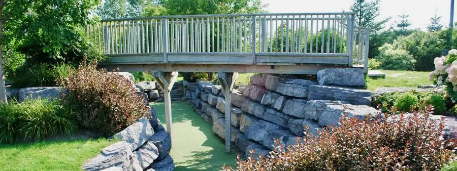 Raised bridge over a mini golf hole with rock walls